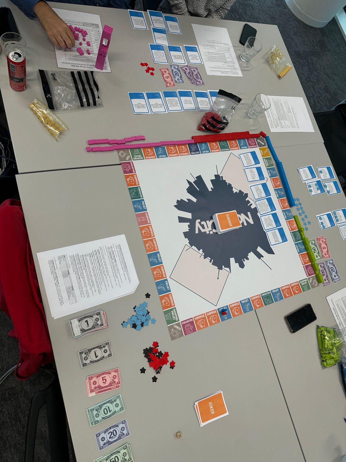 Le plateau Novacity en cours de partie : cases colorées, files de briques de couleur, cartes et jetons.